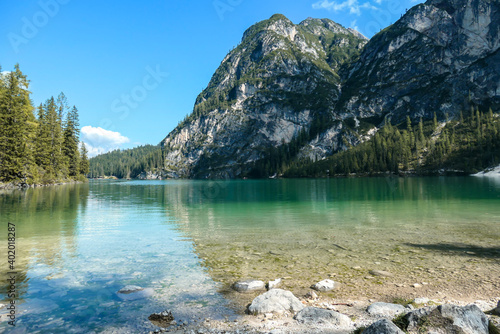 A view on the Pragser Wildsee, a lake in South Tyrolean Dolomites. High mountain chains around the lake. The sky and mountains are reflecting in the lake. Dense forest at the shore. Autumn vibe. Relax