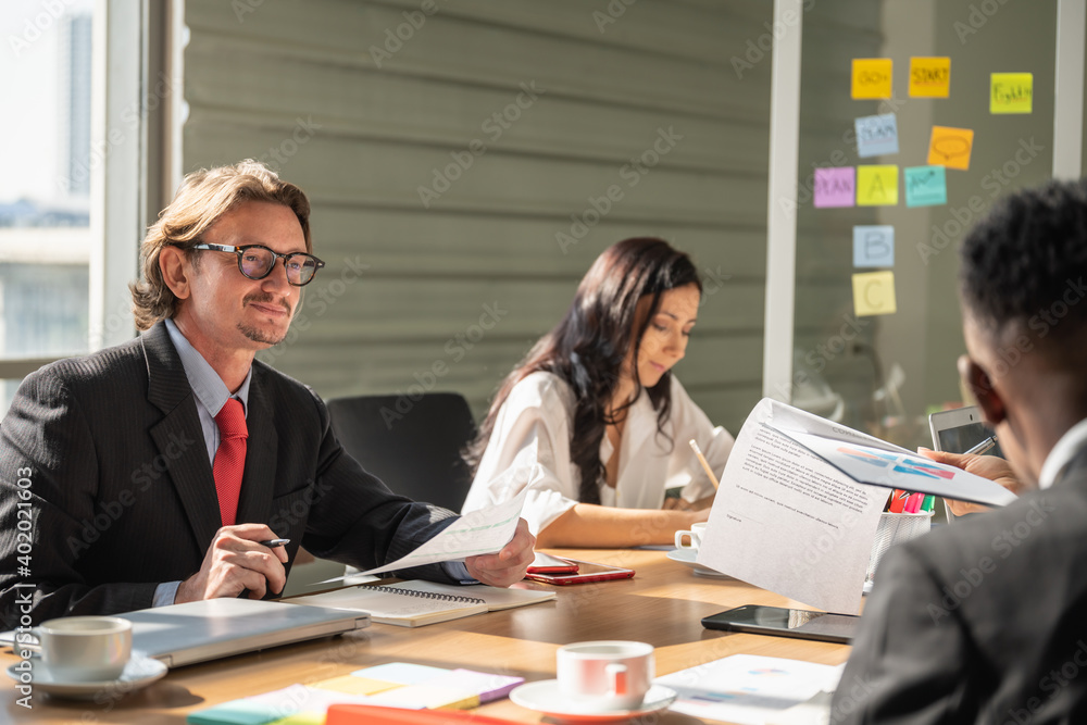 Obraz premium Diversity Business and Work palce concept. Group of businessman and businesswoman team colleague meeting in office with laptop computer, notebook, smartphone, tablet and cup of hot coffee.