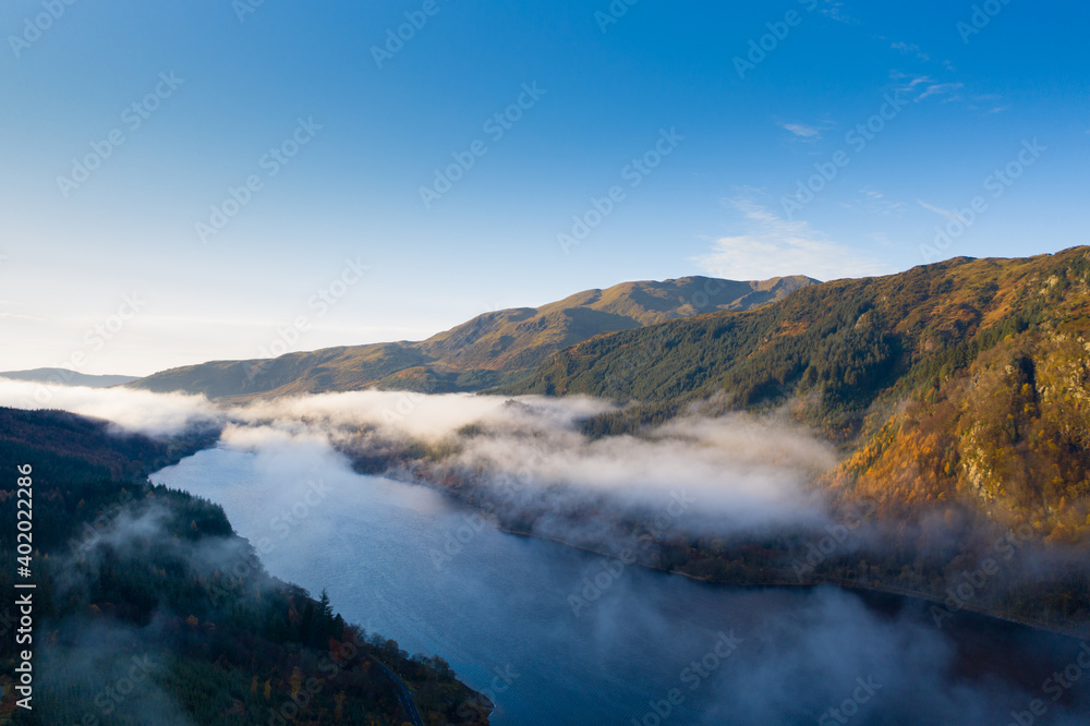 Dramatic valley with casting light and low cloud, mist and lake 
