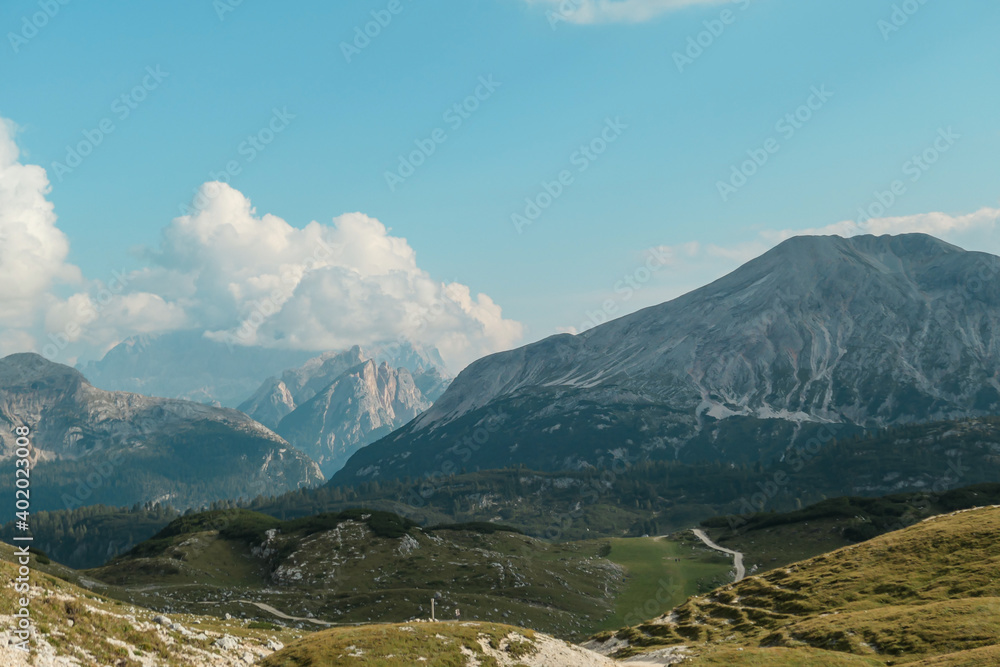 A panoramic view on a high plateau in Italian Dolomites. The meadow is slowly turning golden. High mountain chains in the back. Desolated and remote landscape. Natural habitat. A bit of overcast