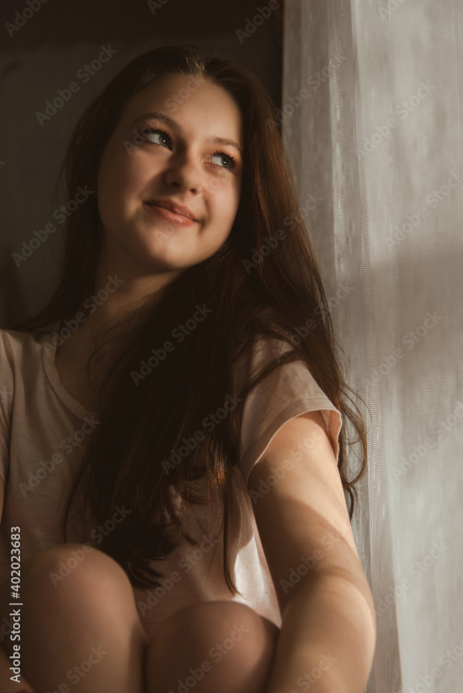 A cute girl is sitting by the window. The girl at the window A cute girl is sitting by the window. The girl at the window