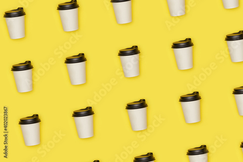 Flat lay paper white cup with back plastic cover pattern on yellow background. High quality photo