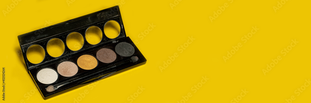 Naklejka premium Eyeshadow palettes with brushes isolated on yellow background. Beauty industry and make-up products. Banner panoramic. Copy space for text message. High resolution sharp photo.