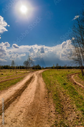 Road through the field before the reaching thunderstorm