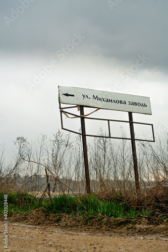 Road sign 'Mikhaylova Zavod' St.' during rain photo