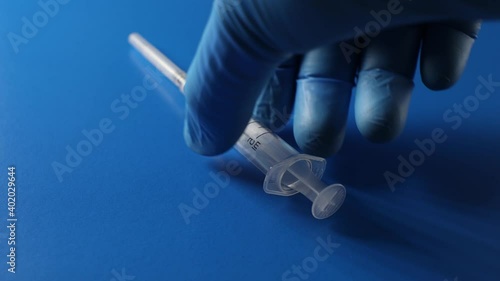 An ampoule with a vaccine and a syringe are on a blue background. The concept of vaccination against coronavirus