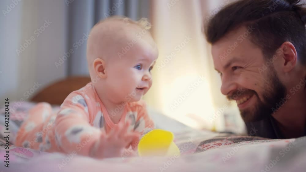 Smiling dad and his little daughter have fun together in the bedroom. Smiling dad and his little daughter have fun together in the bedroom.