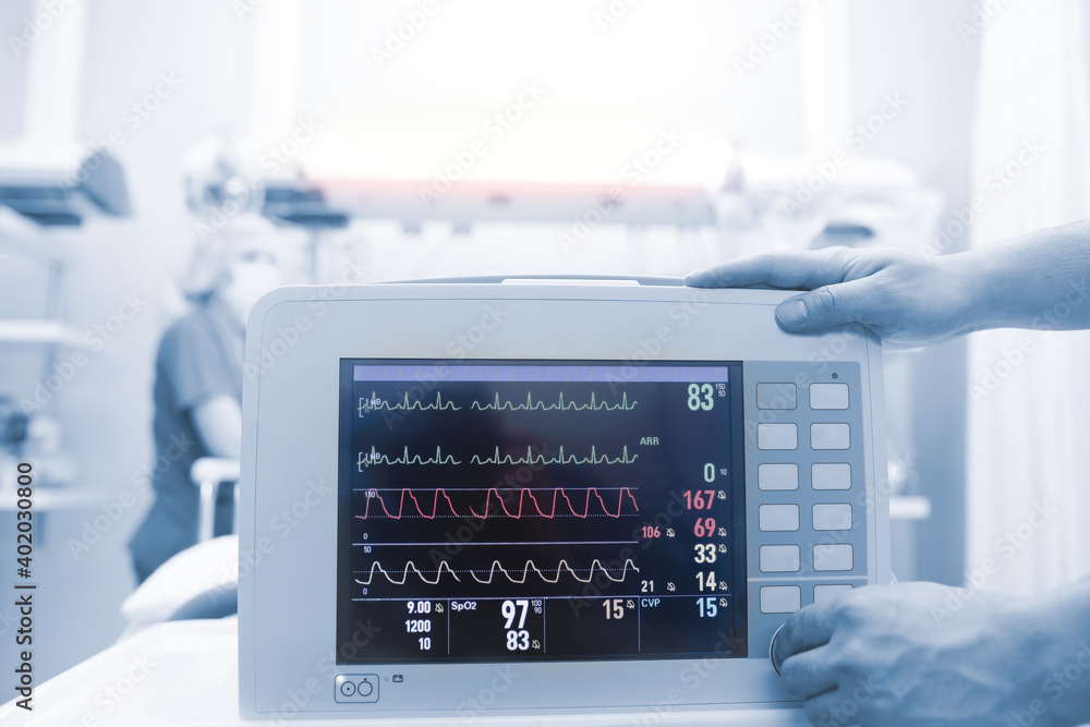 Medical workers connecting critical patient to the heart monitor in the intensive care unit