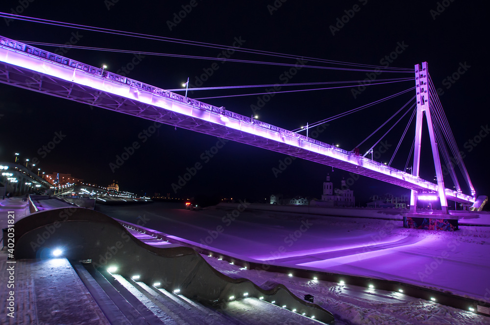 Obraz premium Tyumen, Russia, December 27, 2020: Pedestrian bridge on the embankment at night, in winter