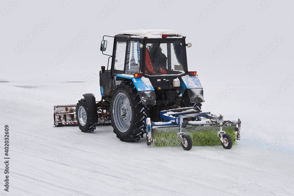tractor with a snow plow and a mechanical sweeper moves on a snowy background tractor with a snow plow and a mechanical sweeper moves on a snowy background
