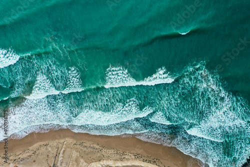 Sea coastline with big waves, above view, beach  background. Ocean surface seashore, seaweed on the water.