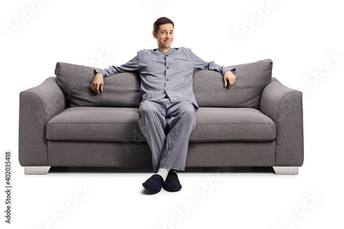 Joyful young man at home in pajamas sitting on a sofa