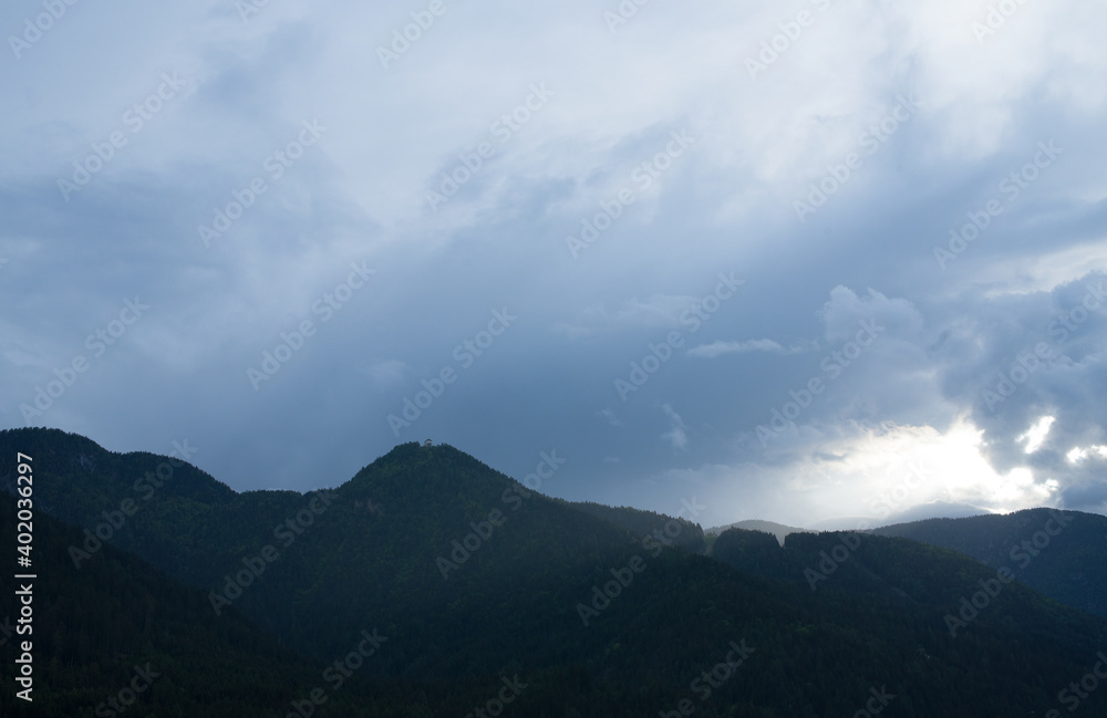 un cielo grigio e cupo sopra un monte coperto di abeti in un paese di montagna