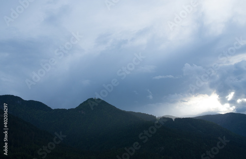 un cielo grigio e cupo sopra un monte coperto di abeti in un paese di montagna