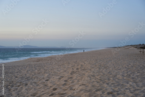 Fisherman fishing on a Comporta empty beach at sunset in Portugal