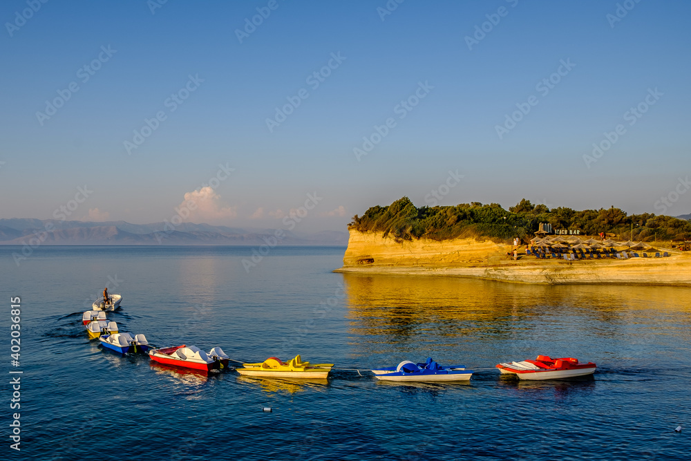 Fototapeta premium A small boat tugging a line of colorful catamarans