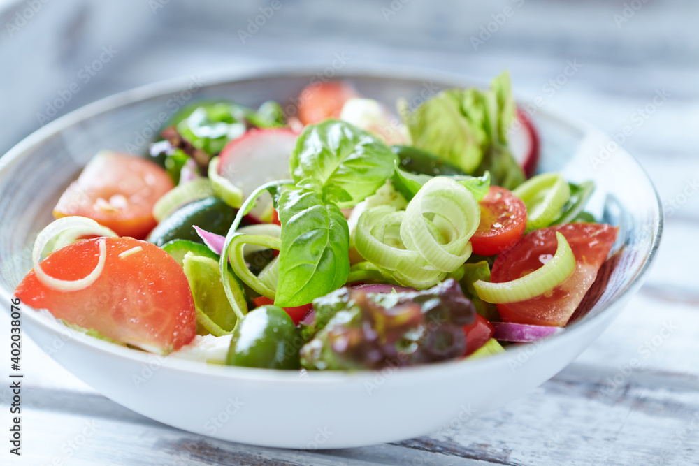 Salad with feta cheese, radish, rocket, green olives, tomatoes, cucumber and fresh basil. Bright wooden background. Close up. Salad with feta cheese, radish, rocket, green olives, tomatoes, cucumber and fresh basil. Bright wooden background. Close up.