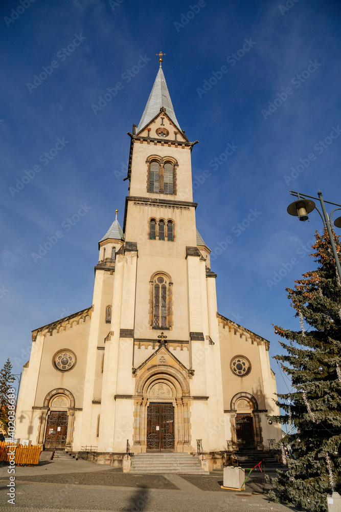 Gothic church of the Assumption of the Virgin Mary, with bell tower, Christmas market at Square Namesti starosty Pavla in Kladno in sunny day, Central Bohemia, Czech Republic