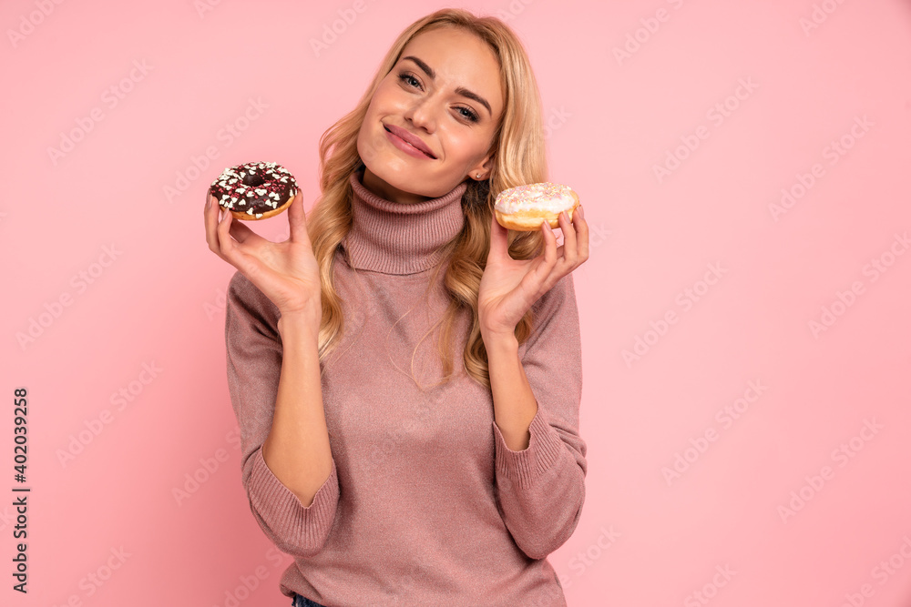 Portrait of an excited young woman showing donuts isolated over pink background Portrait of an excited young woman showing donuts isolated over pink background