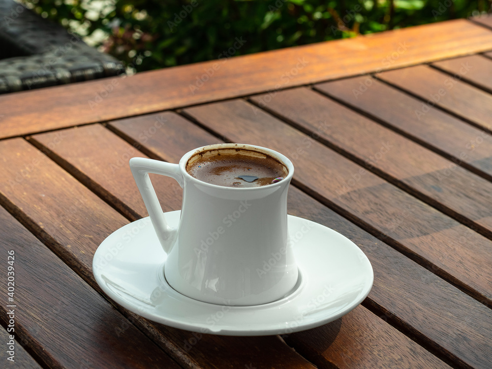 A Cup of coffee stands on a table made of wooden slats. The photo was taken on a sunny summer day. The table is in the aunt of trees. A Cup of coffee stands on a table made of wooden slats. The photo was taken on a sunny summer day. The table is in the aunt of trees.