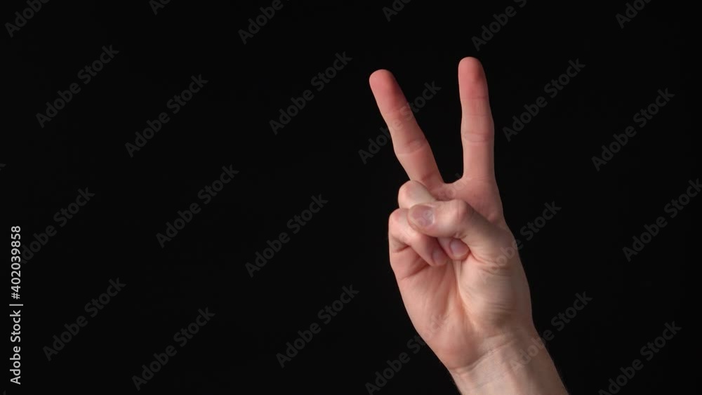Young caucasian man's hand showing victory sign on black background. Isolated Young caucasian man's hand showing victory sign on black background. Isolated