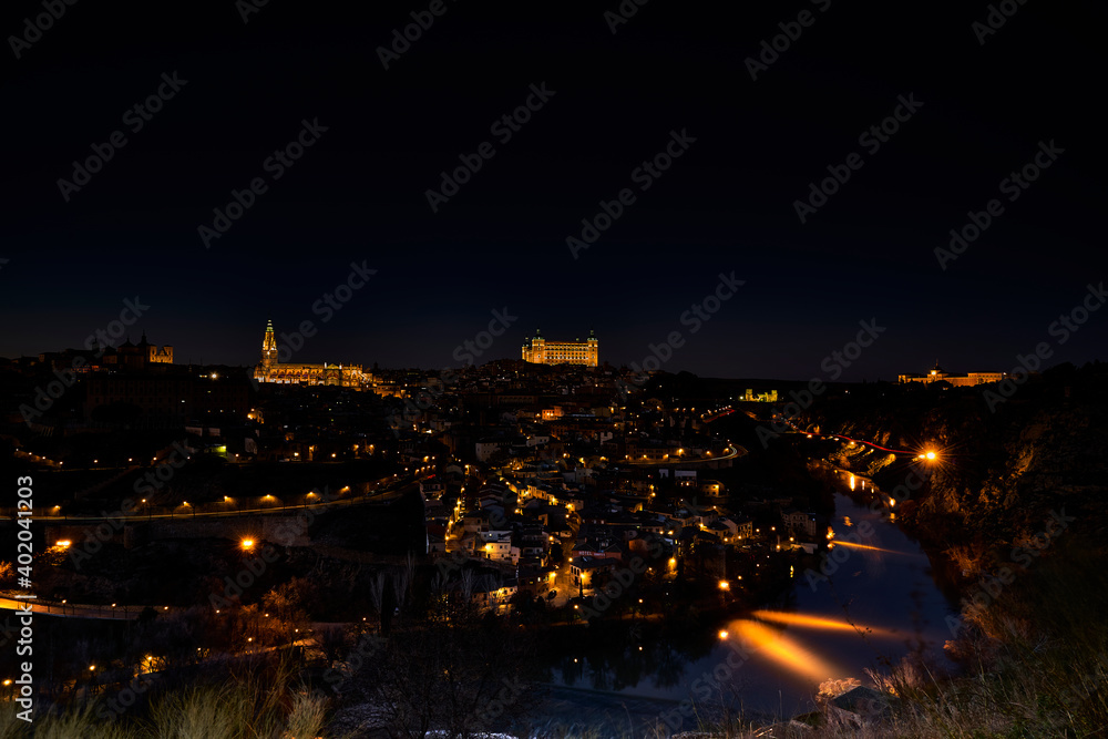 vista de Toledo  iluminado de noche con el rio tajo y se ve la catedral y el alcazar