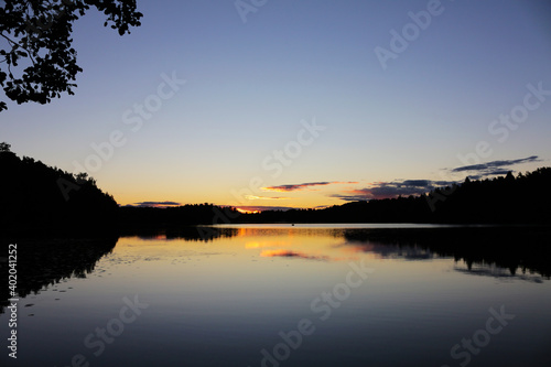 Peaceful evening at the lake. Reflection of the sky and clouds in calm water. Beautiful landscape with Finnish nature.