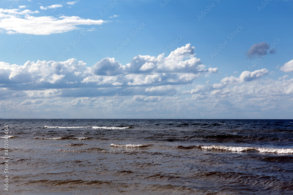 Beautiful landscape overlooking the Baltic Sea with small waves and cloudy blue skies.
