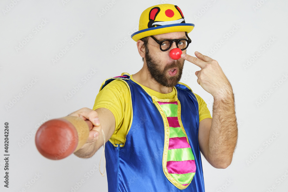 The clown is a man in a bright blue and yellow suit with a baseball bat. The clown is a man in a bright blue and yellow suit with a baseball bat.