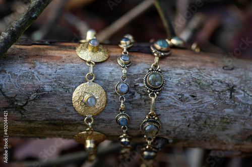 Three brass bracelets with labradorite stone on wooden background
