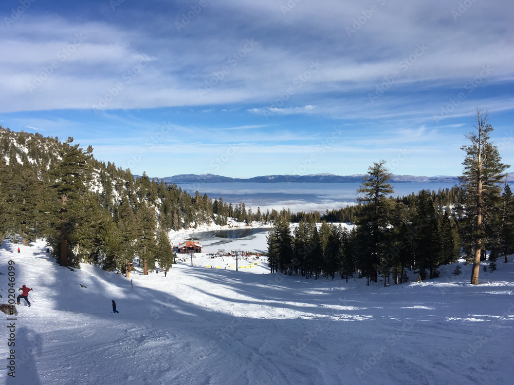 Scenic winter landscape at a ski resort, with skiers on slopes, on a cloudy day Scenic winter landscape at a ski resort, with skiers on slopes, on a cloudy day