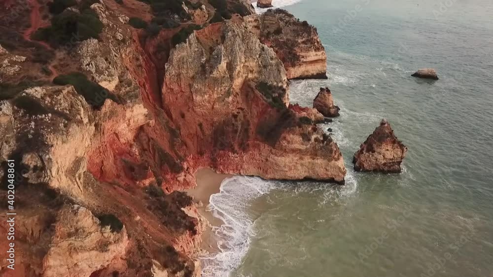 Lagos Portugal Atlantic ocean drone shot aerial view look over blue water waves sunrise morning limestone coastline sea pillars hidden grottos Praia de Dona Ana flying towards Lagos Portugal Atlantic ocean drone shot aerial view look over blue water waves sunrise morning limestone coastline sea pillars hidden grottos Praia de Dona Ana flying towards