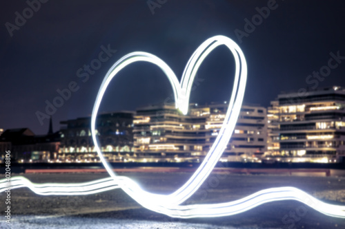 Light Painting Art: Heart painted with light into darkness with the skyline of a big city in the background