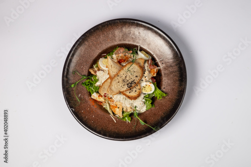 Caesar salad with grilled chicken fillet and slices of bacon, with tomatoes and Caesar sauce. Sprinkled with Parmesan cheese with wheat croutons and quail egg. on a white background. top view