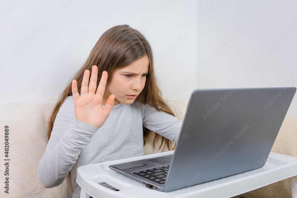 Emotional portrait of attractive cute girl 6-7 old she is tired in a bad mood sitting using laptop on distance learning Emotional portrait of attractive cute girl 6-7 old she is tired in a bad mood sitting using laptop on distance learning