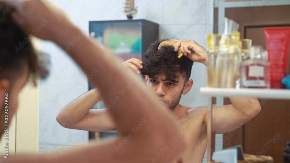 Young man combing hair in bathroom Young man combing hair in bathroom