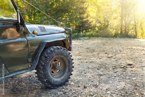 Old retro vintage 4x4 convertible suv vehicle on dirt gravel unpaved road in summer at sunset morning sun. Off road car mountain safari adventure nature trip journey concept. Soft shallow focus