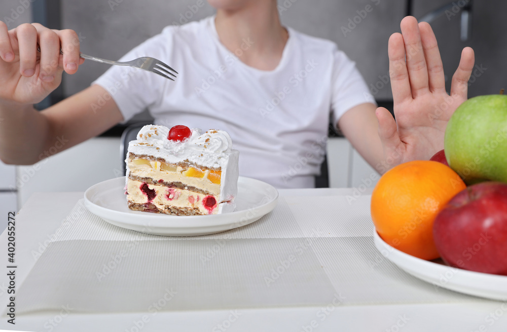 Child choosing to eat cake instead of fruits. Sugar addiction , unhealthy lifestyle concept