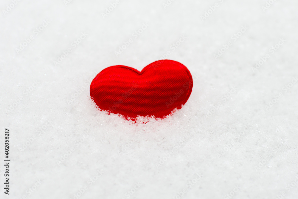 a little red heart lies in the snow. Horizontal photo. The idea is love, to give love on Valentine's Day.