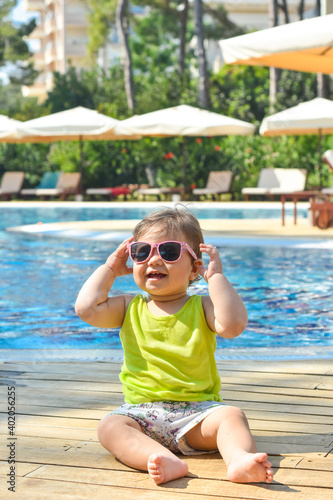 Cute adorable baby crawls near swimming pool. Summer vacation with children. Family on resort. Summer holiday concept. Child alone near water. © Ersin