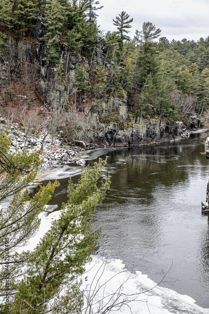 Rocky cliffs along the winter snow and icy river Rocky cliffs along the winter snow and icy river