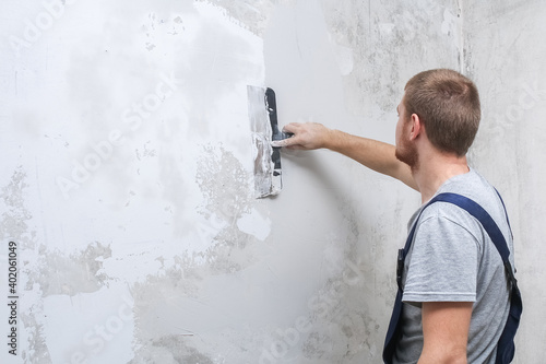 A male worker spreads the putty mixture and flattens the wall. photo