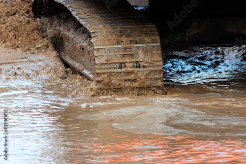 excavator tracks in the water. repair and expansion of a road in the north of gatchina, russia. reportage shooting.