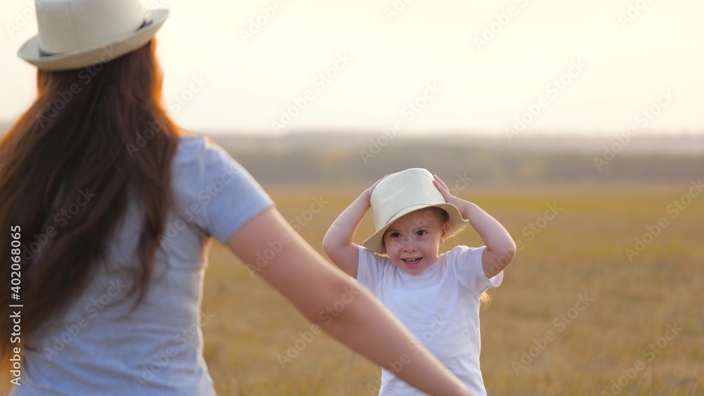 Happy little daughter loves mom, child and mother hug in park. Mom and baby hug. Happy family, mom and daughter in field play on grass. Concept of happy family and healthy children. Baby loves mommy