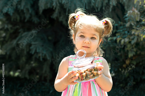 Portrait of cute baby girl holding candies from during Ramadan feast  aka  Ramazan or Seker bayrami . Sweets in little child hands as a tradition in middle eastern culture.