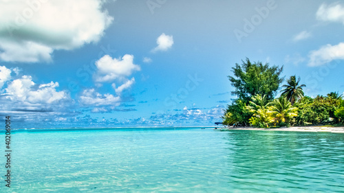 Polynesian island, the turquoise sea and the white clouds in the blue sky create a peaceful scene