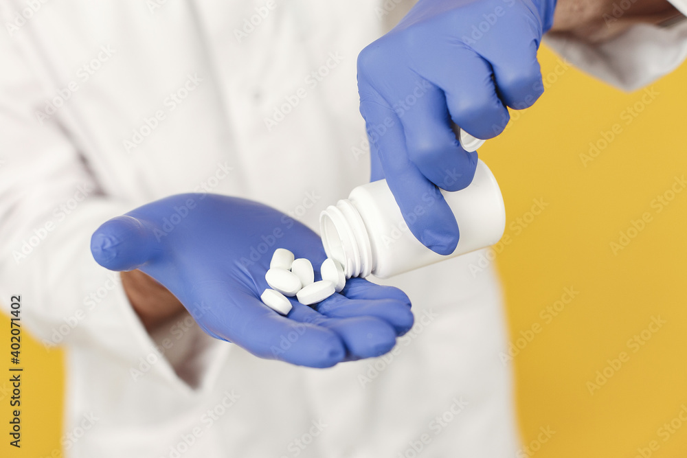 Smiling medical doctor with pills. Isolated over yellow background. Man in a blue gloves. Smiling medical doctor with pills. Isolated over yellow background. Man in a blue gloves.