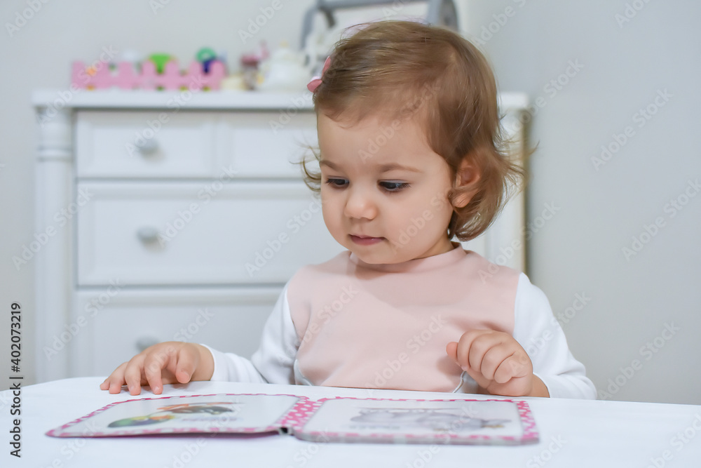 Cute adorable baby girl reading a book at home or kindergarten. 