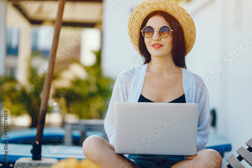 brunette girl working on her computer by the pool