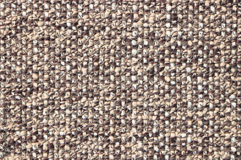 Fototapeta premium Sample of a beige brown fabric with a pronounced weave of threads. Textiles and wool. Blank background and close-up.